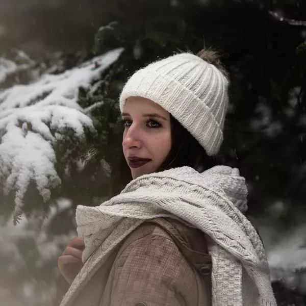 Frau mit Schnee vor einem Tannenbaum